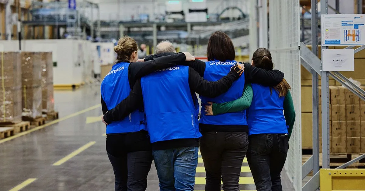 Four workers hugging each other at a warehouse.