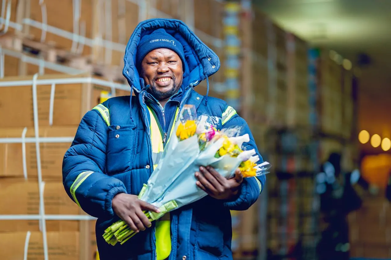 A Kuehne+Nagel employee happily poses with a bouquet of fresh flowers.