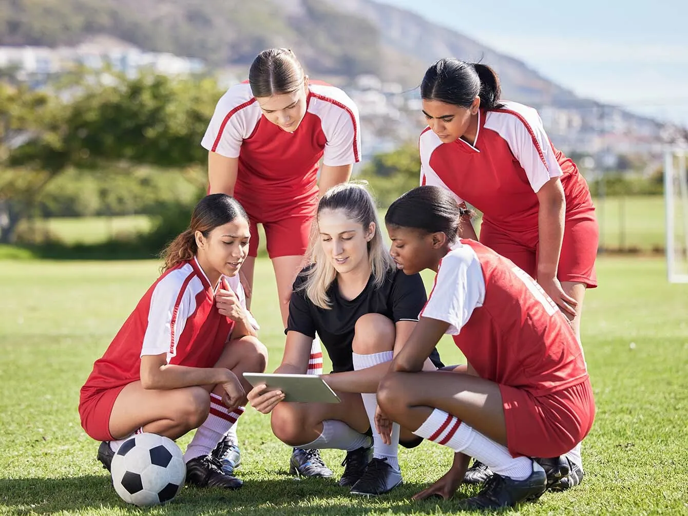 Female football team with their trainer on the football field preparing for the game