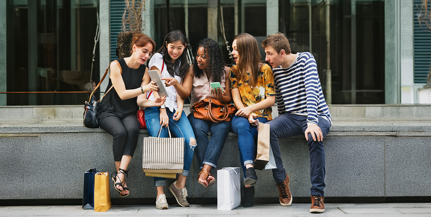 Group of people reacting to a video on a tablet, holding shopping bags