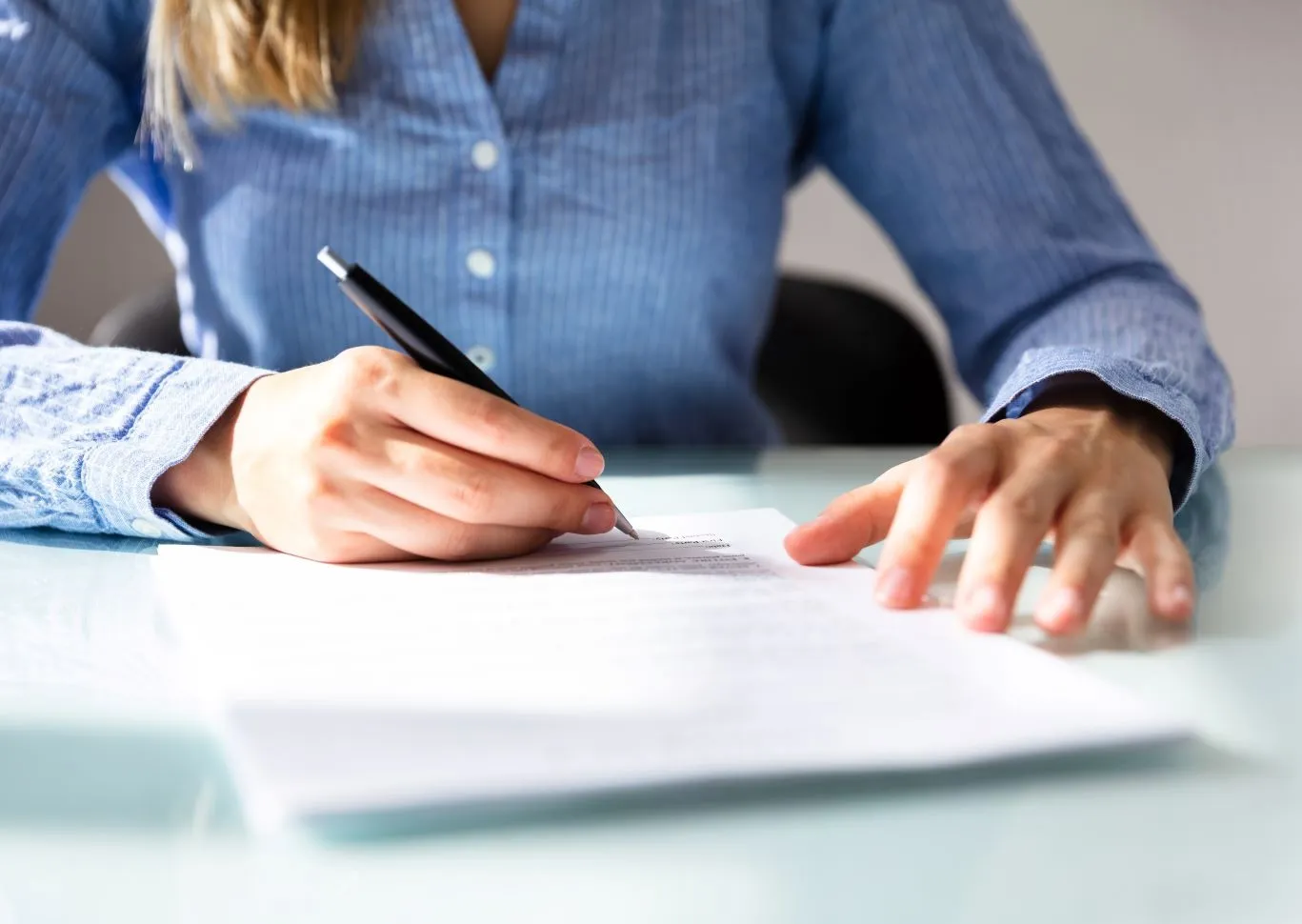Woman signing a document with a black pen.