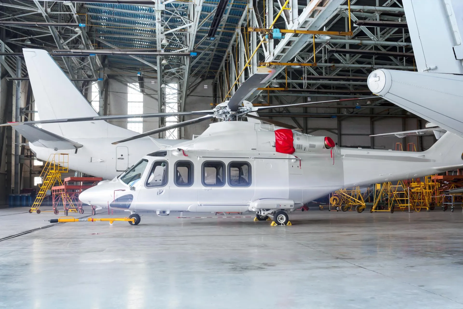 Passenger helicopter and airplanes under maintenance. Checking mechanical systems for flight operations. Rotorcraft of aircrafts in the hangar