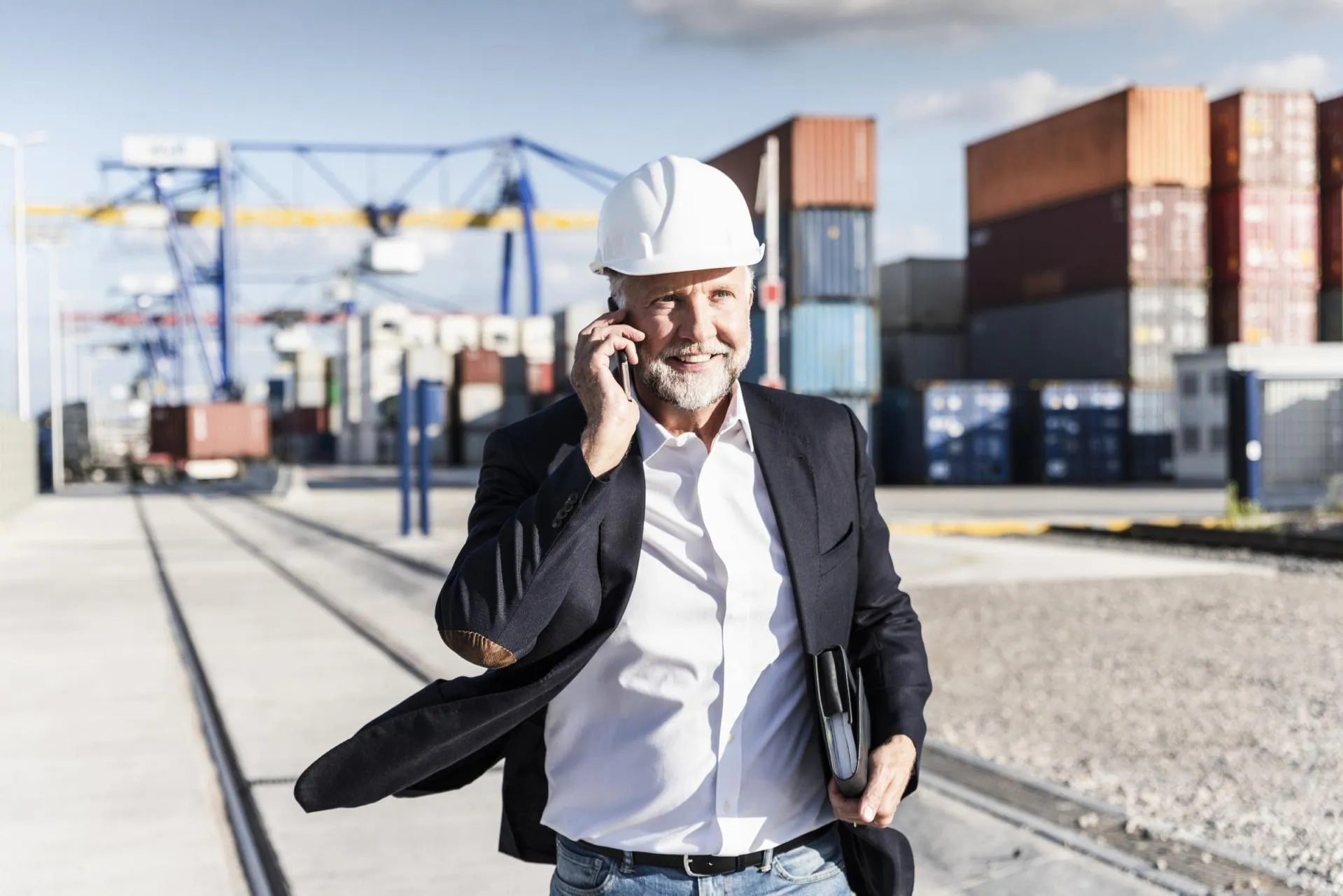 A businessman talking on the phone at a cargo dock.