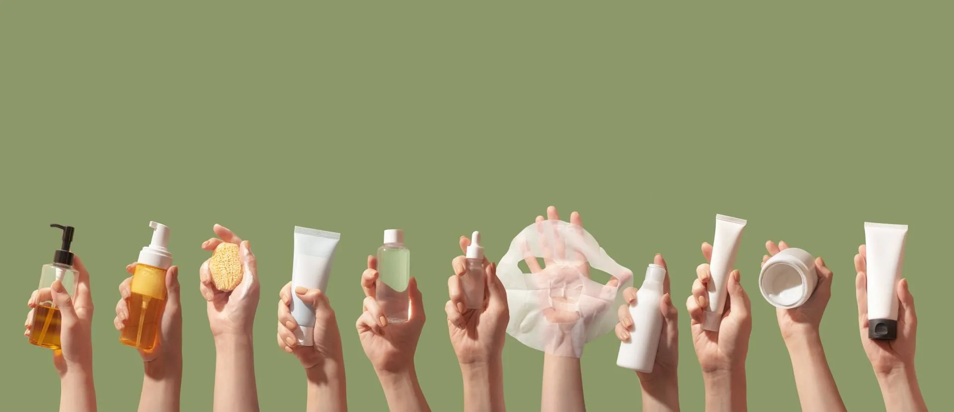Hands holding various bottles and containers of different skincare and haircare products