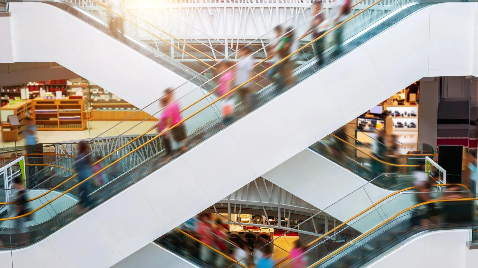 People on many fast moving escalators in modern shopping mall