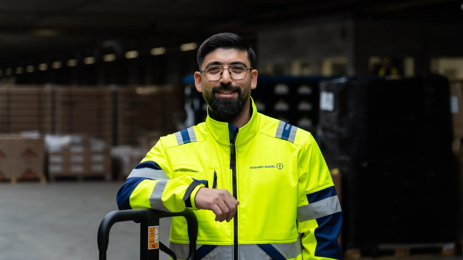 KN driver in yellow reflective jacket standing in a warehouse
