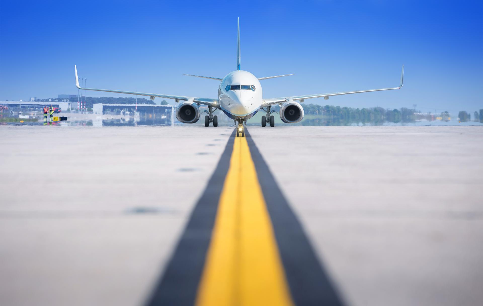 Front view of a commercial aircraft on an airport taxiway, centered on the yellow guidance line.