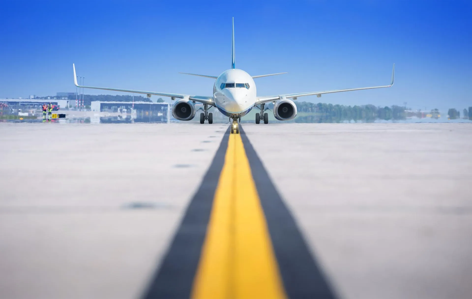 Front view of a commercial aircraft on an airport taxiway, centered on the yellow guidance line.