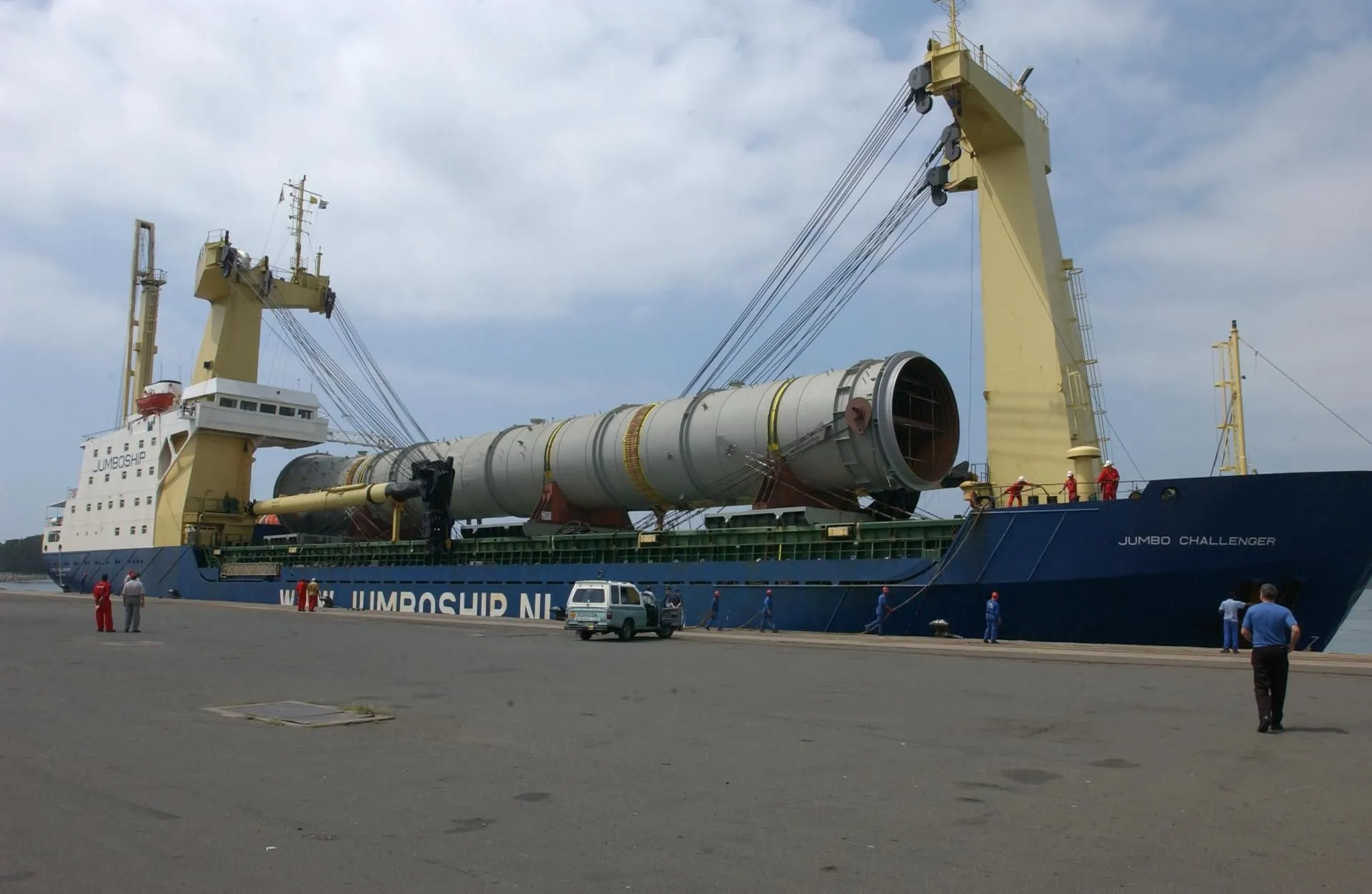 Big ship in harbor carrying a large industrial pipeline.