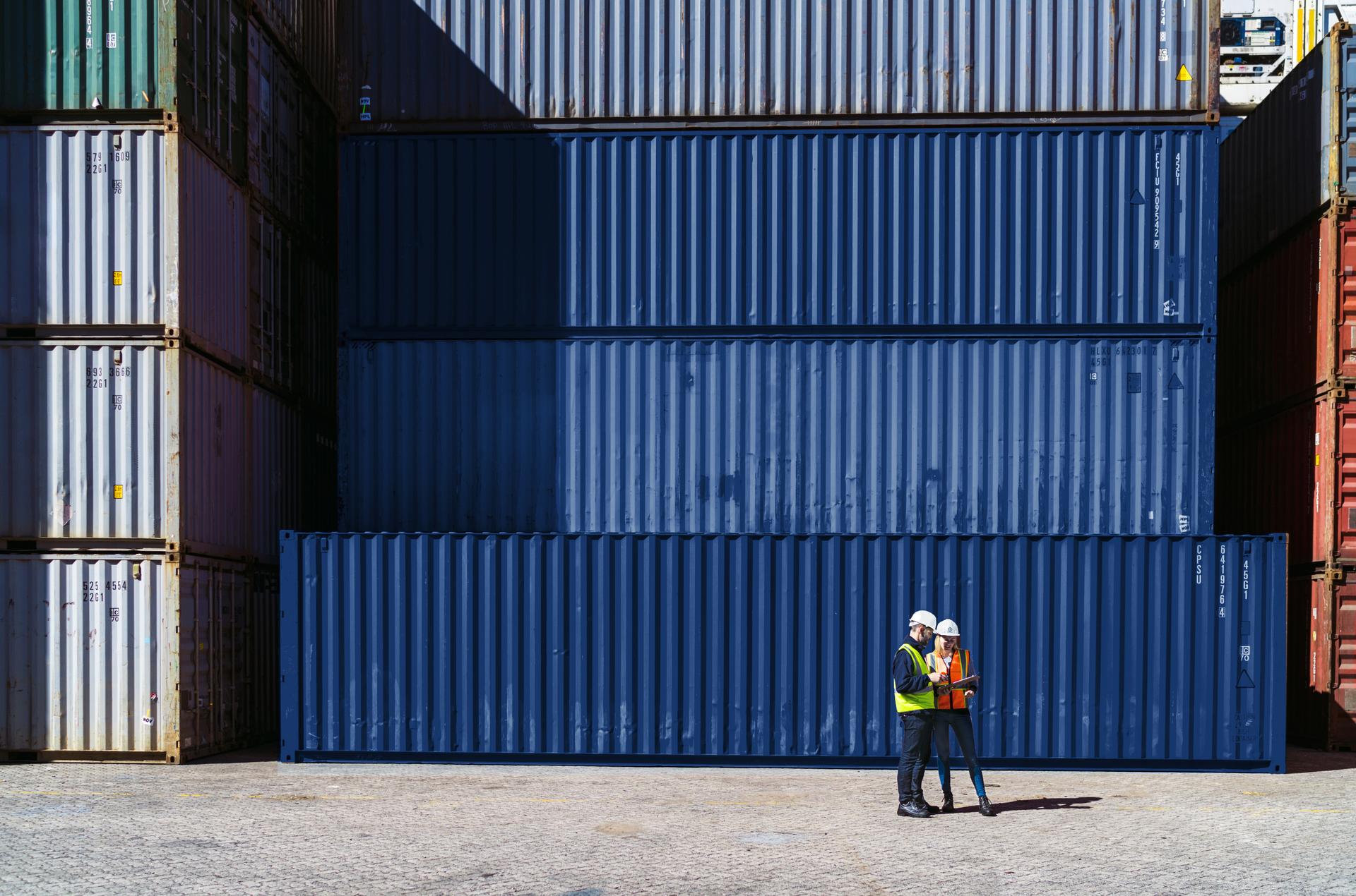 Workers having discussion against cargo containers