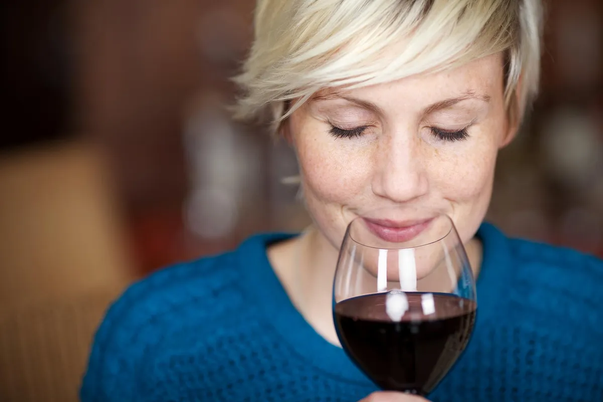 Women in blue sweater drinking red wine