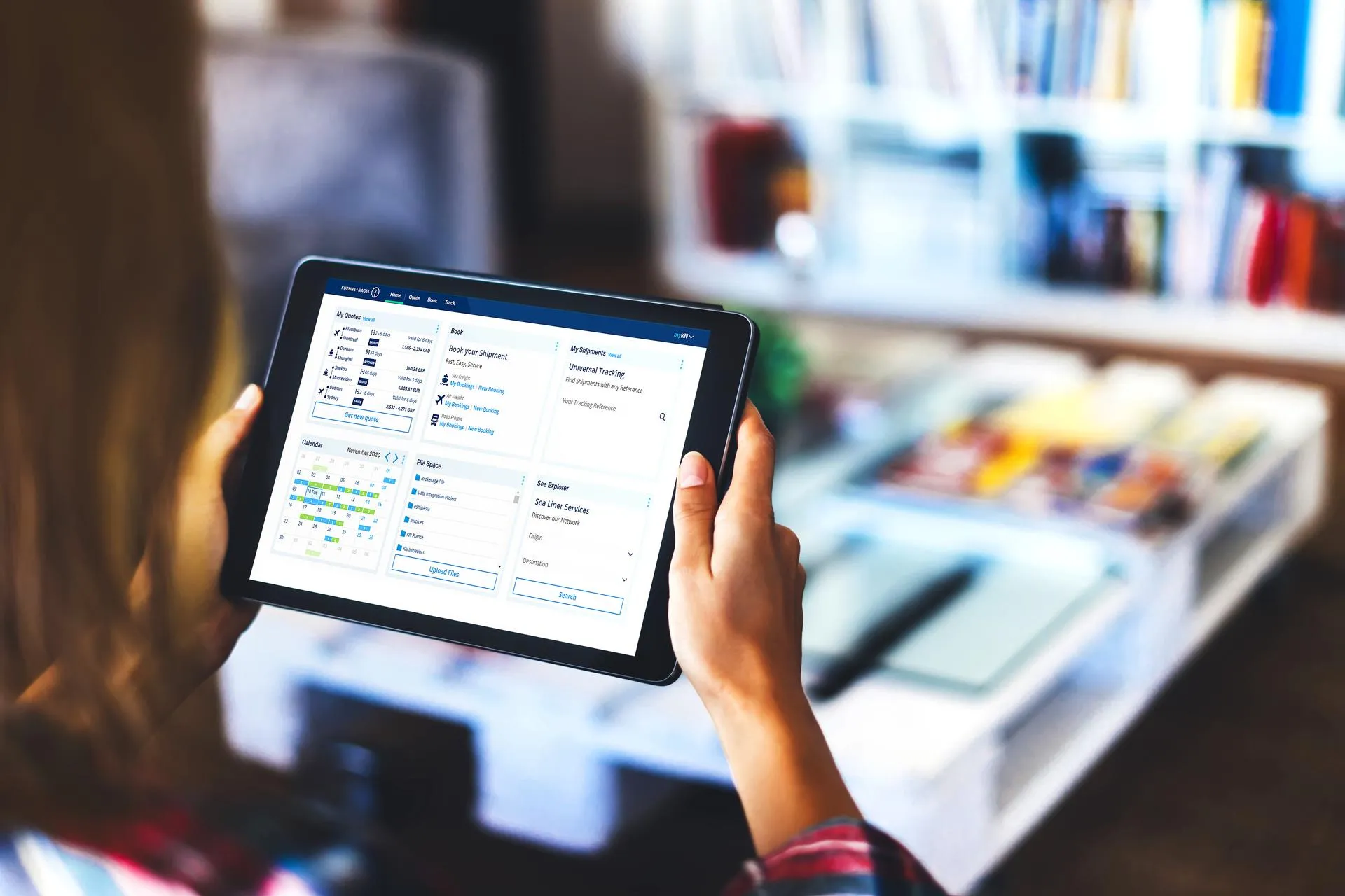 A person holding a tablet with the Kuehne+Nagel MyKN app open in a bookstore.