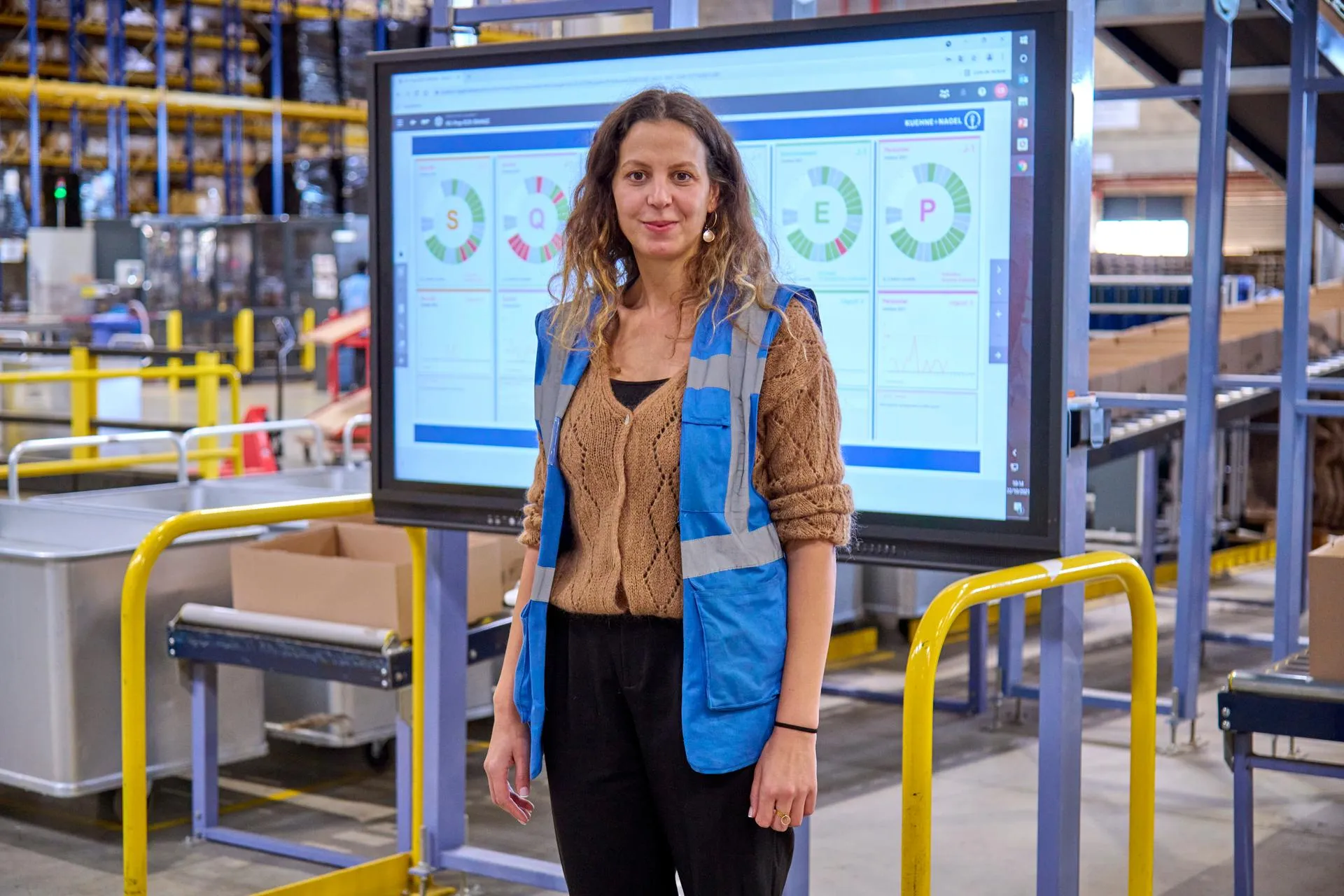 Female worker in the Warehouse with big screen with a dashboard