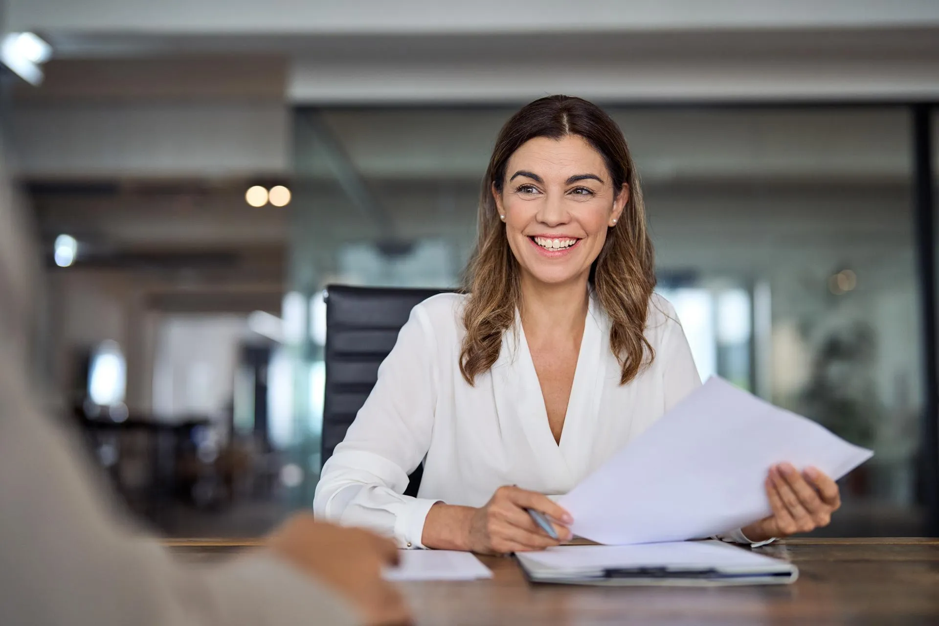 Smiling woman in an office holding some official papers