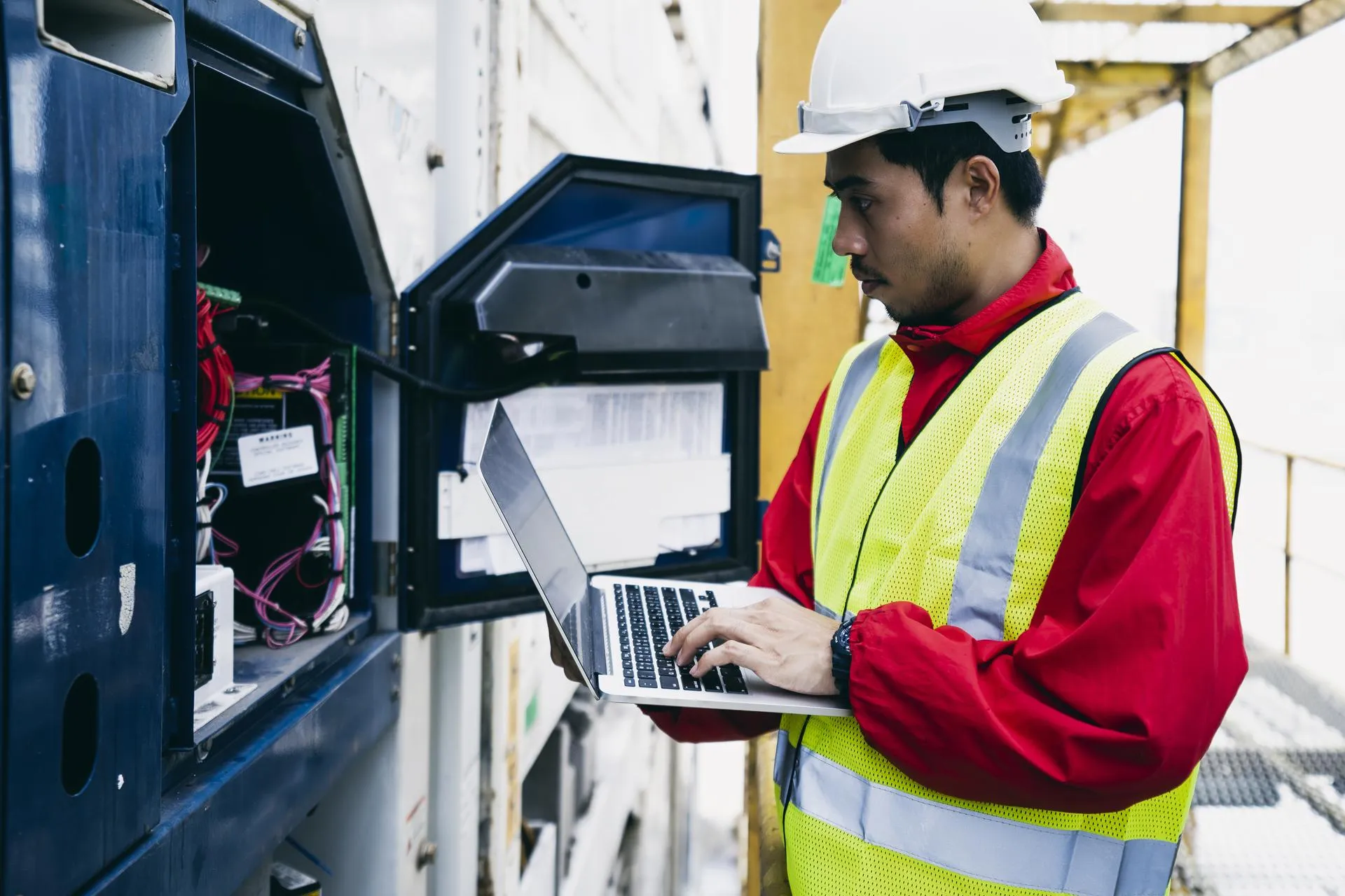 Technician conducting diagnostics on industrial equipment using a laptop