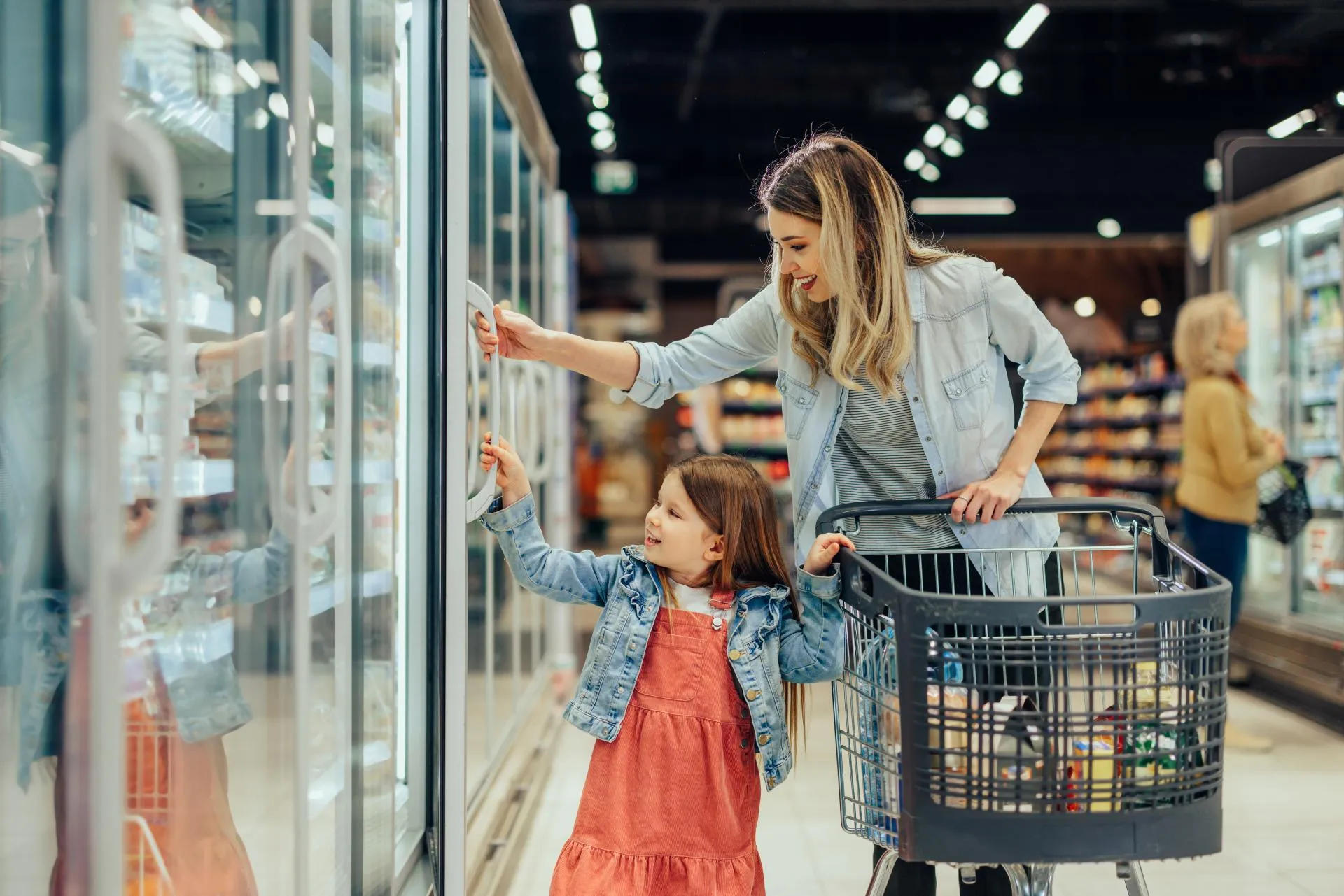 A young woman is shopping in a supermarket with her small child