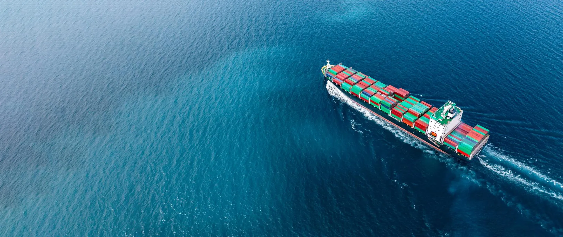 Cargo ship sails through calm blue waters with containers stacked on top