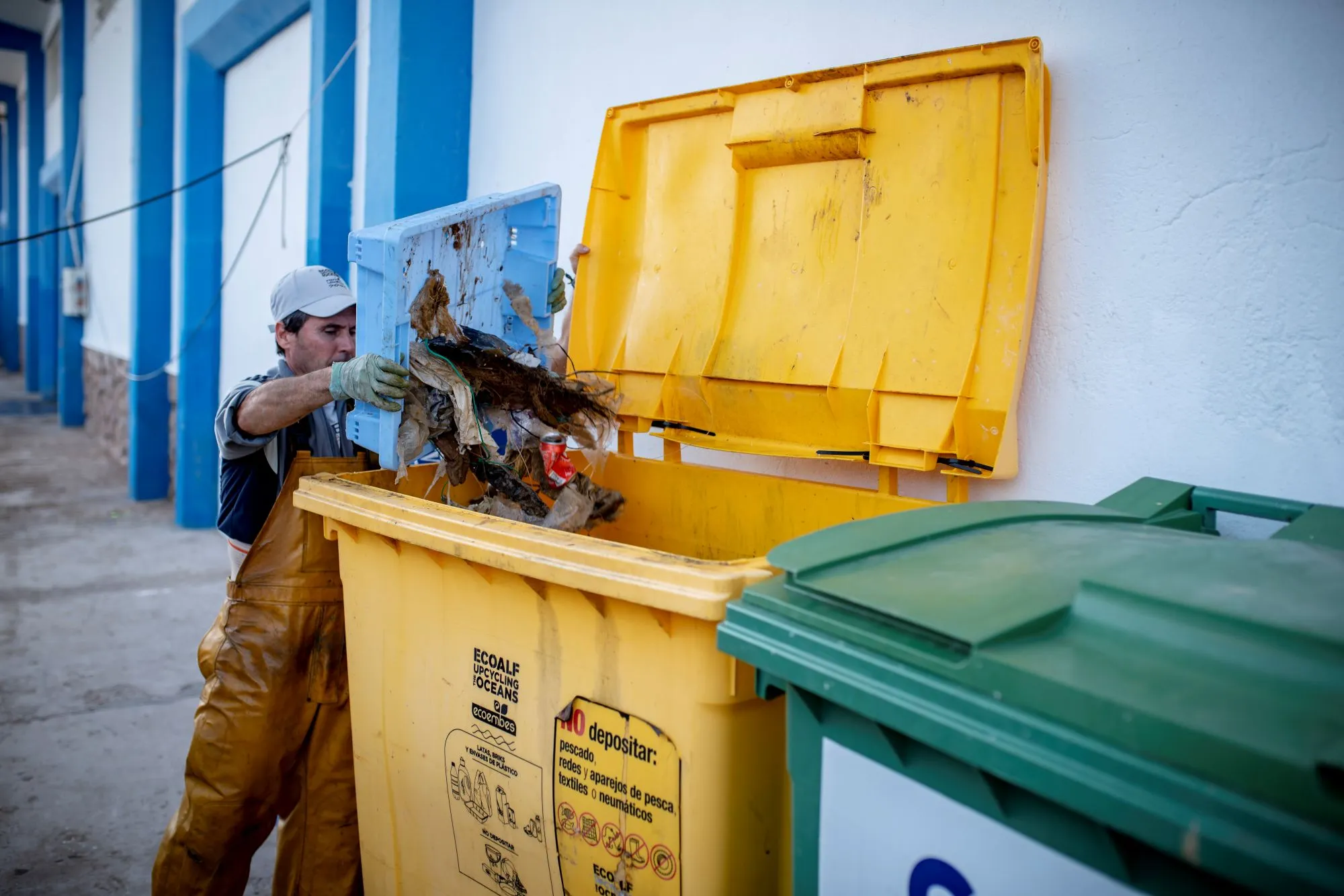A man throwing away waste into a yellow container.