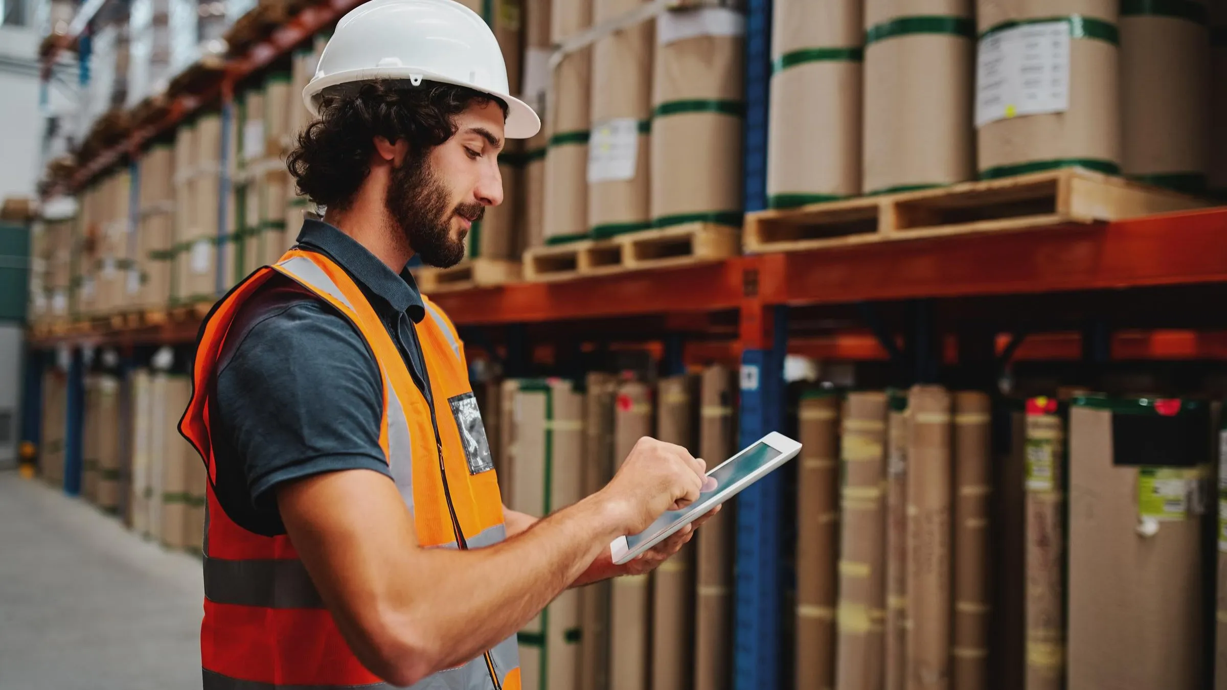 Warehouse worker reading and scrolling on a tablet.