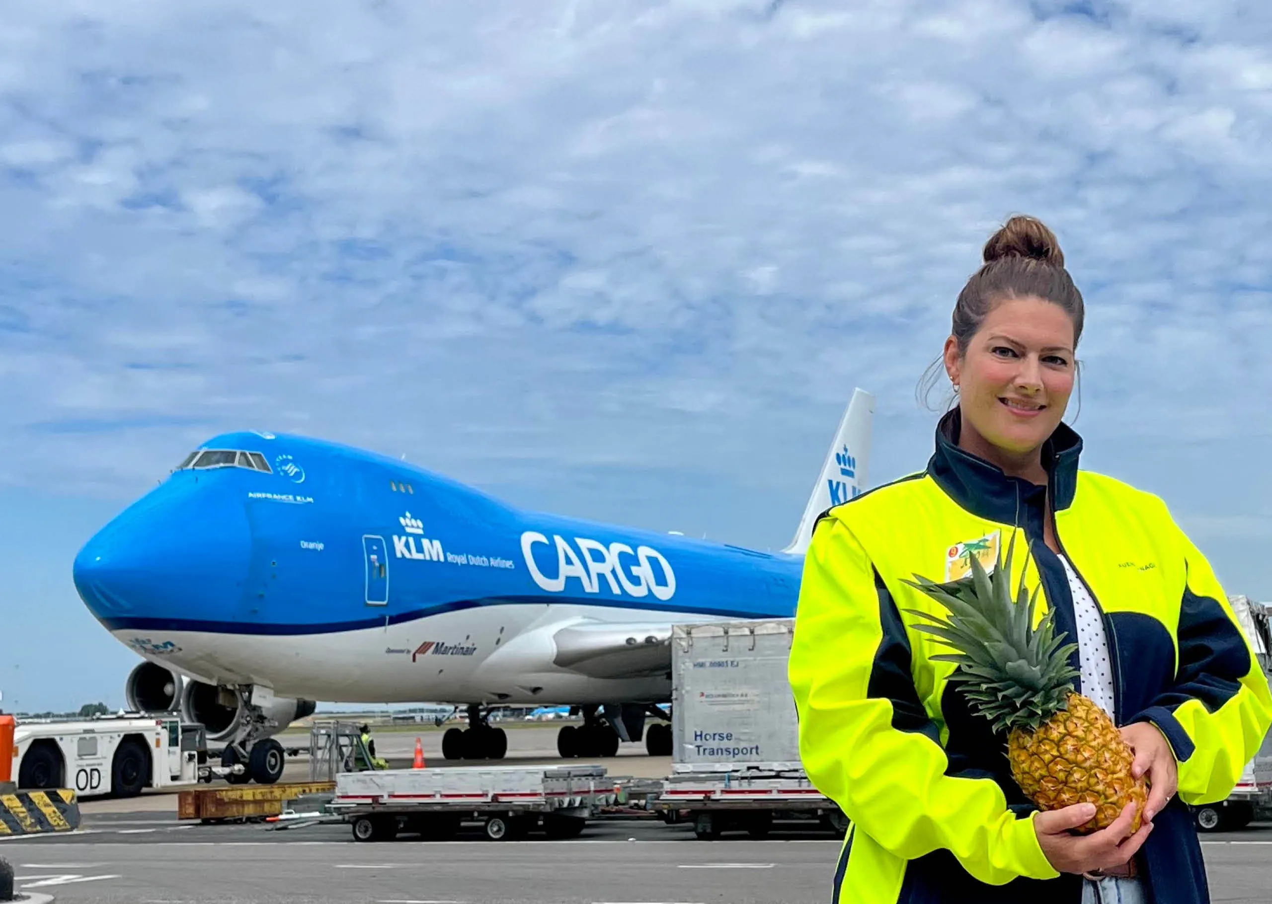 A perishable logistics expert holding a pineapple in front of a plane