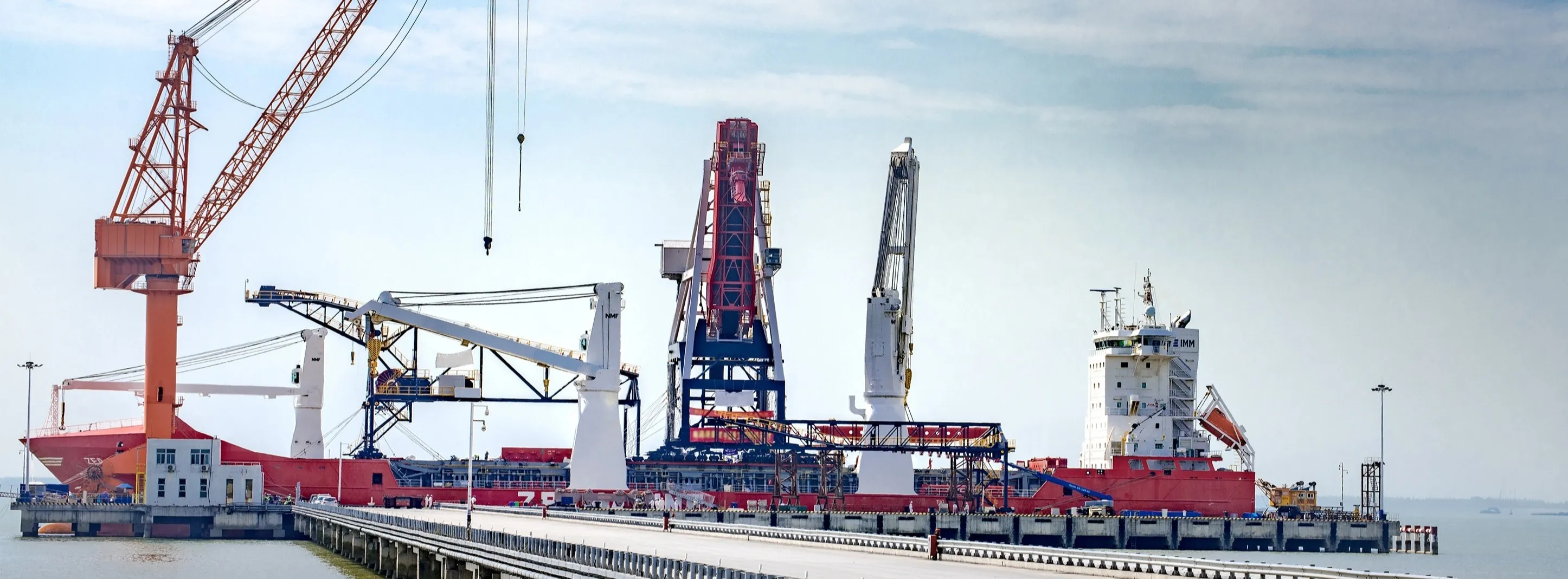 A cargo ship is being loaded at the dock.