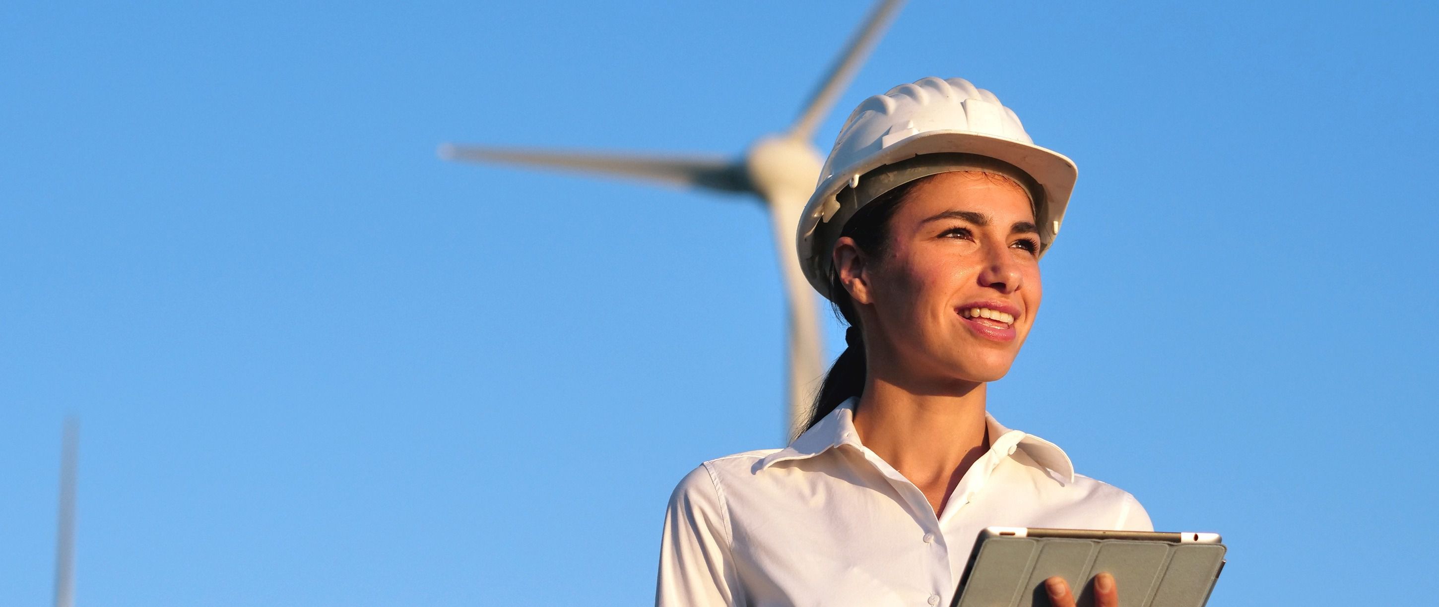 Người phụ nữ đứng trước một tuabin gió.