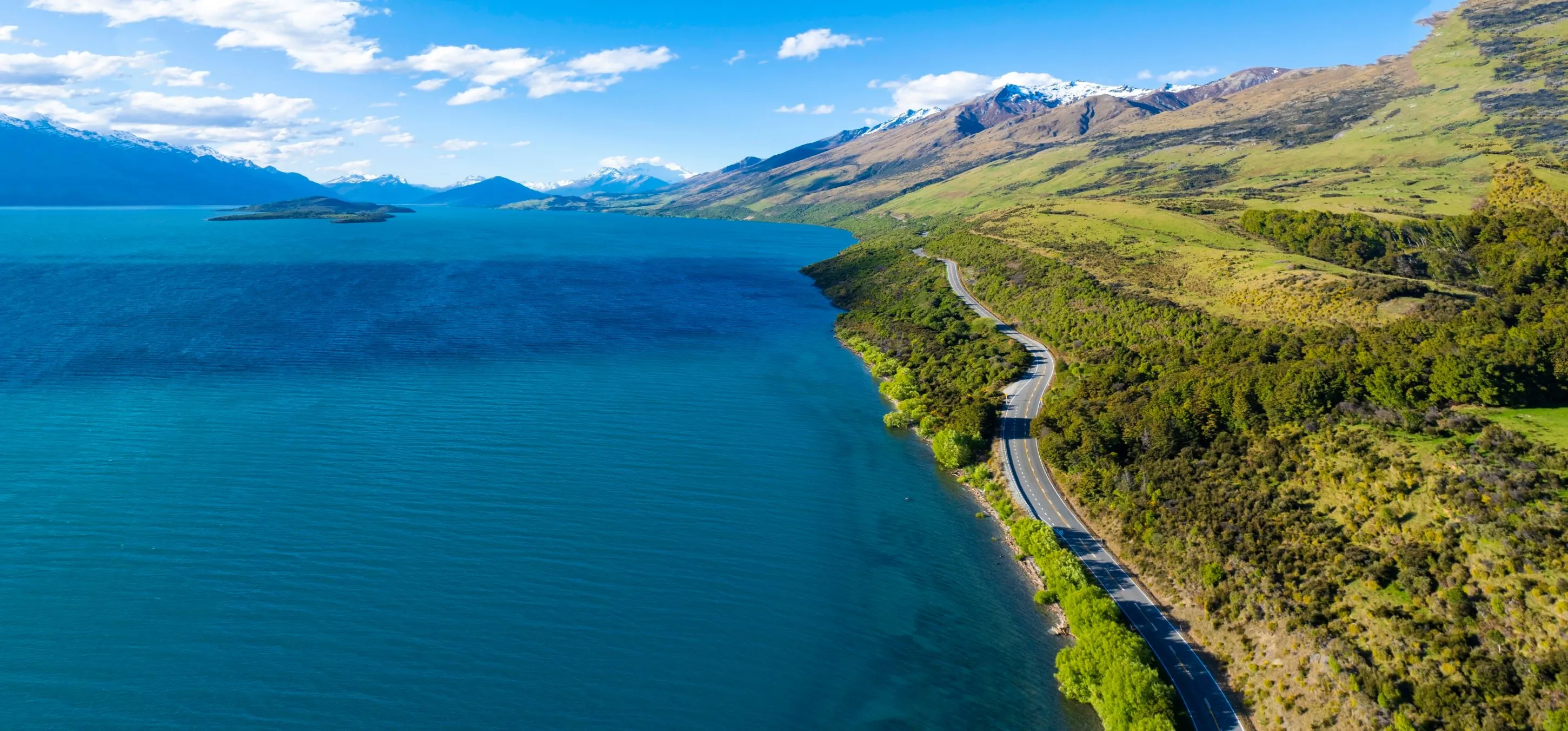 Landscape with a road leading a long a lake with blue sky in the back