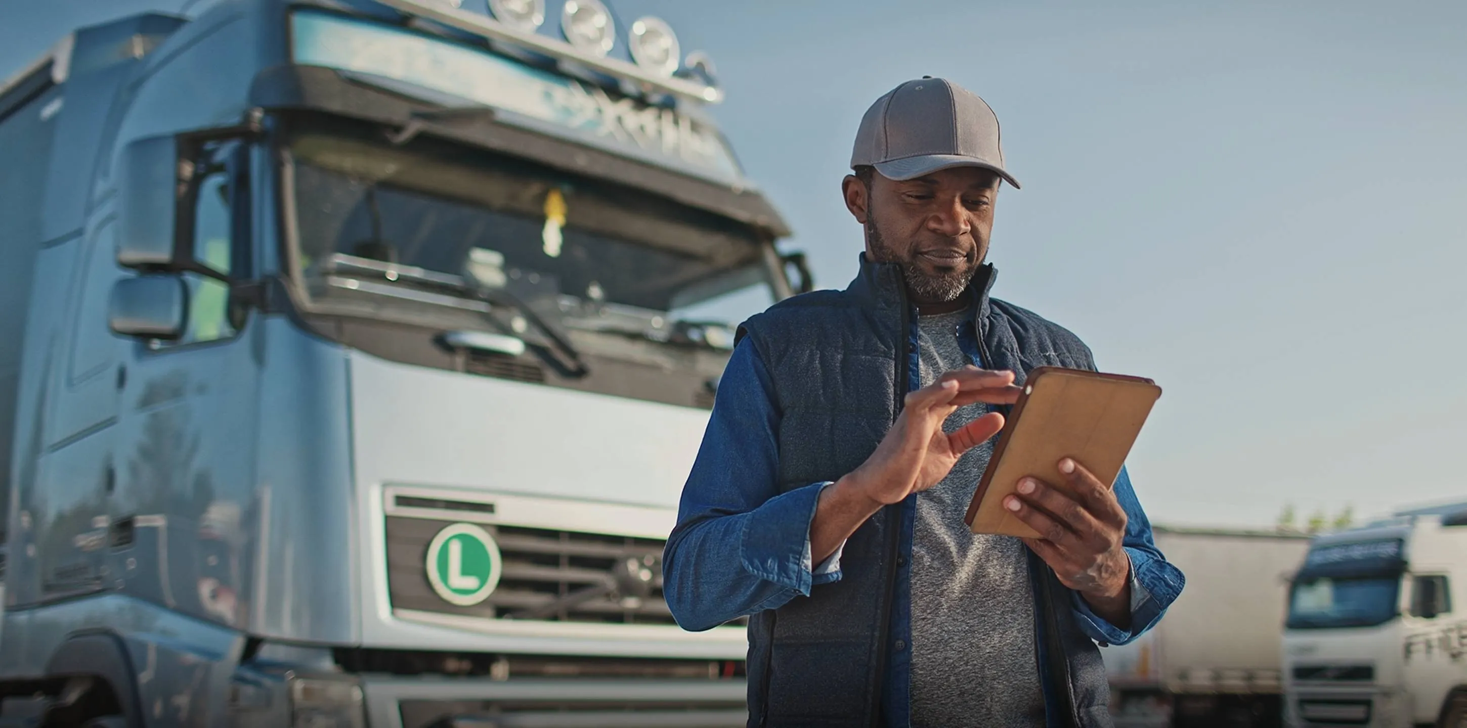 Driver using his tablet device while standing next large truck