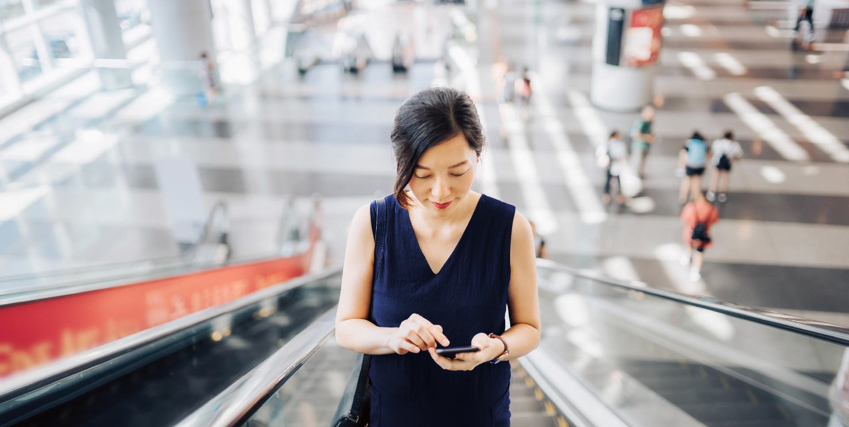 Woman with a smartphone on an escalator