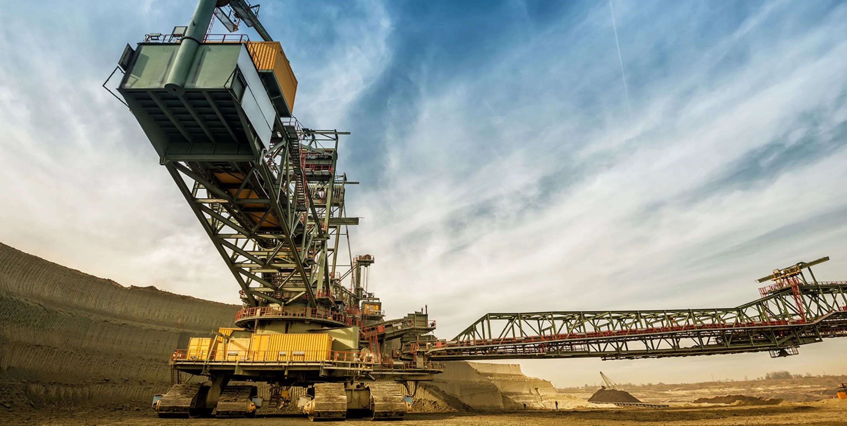 Large industrial mining machine in an open-pit mine under a blue sky with clouds