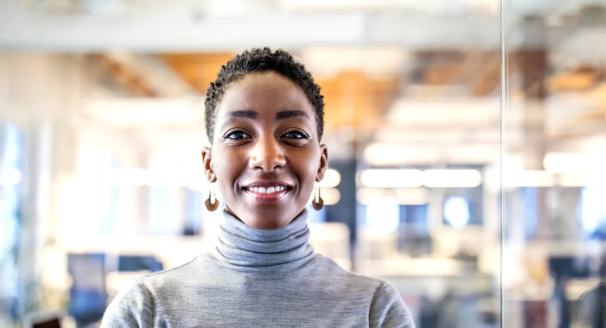 A coloured woman in an office smiling at you