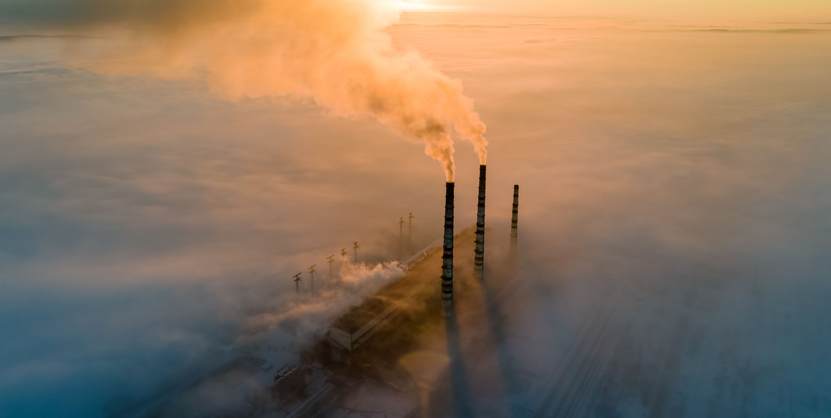 Aerial view of coal power plant high pipes with black smoke moving up polluting atmosphere at sunset