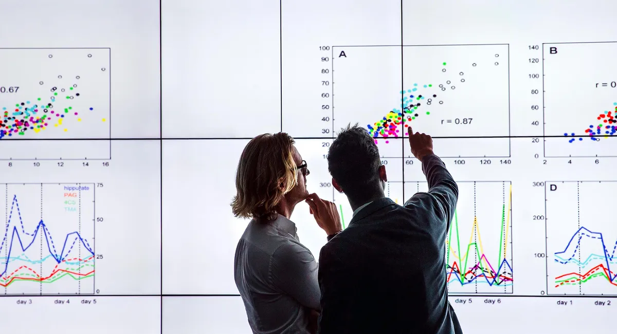 Researchers analyzing neural data trends and correlations on a large display