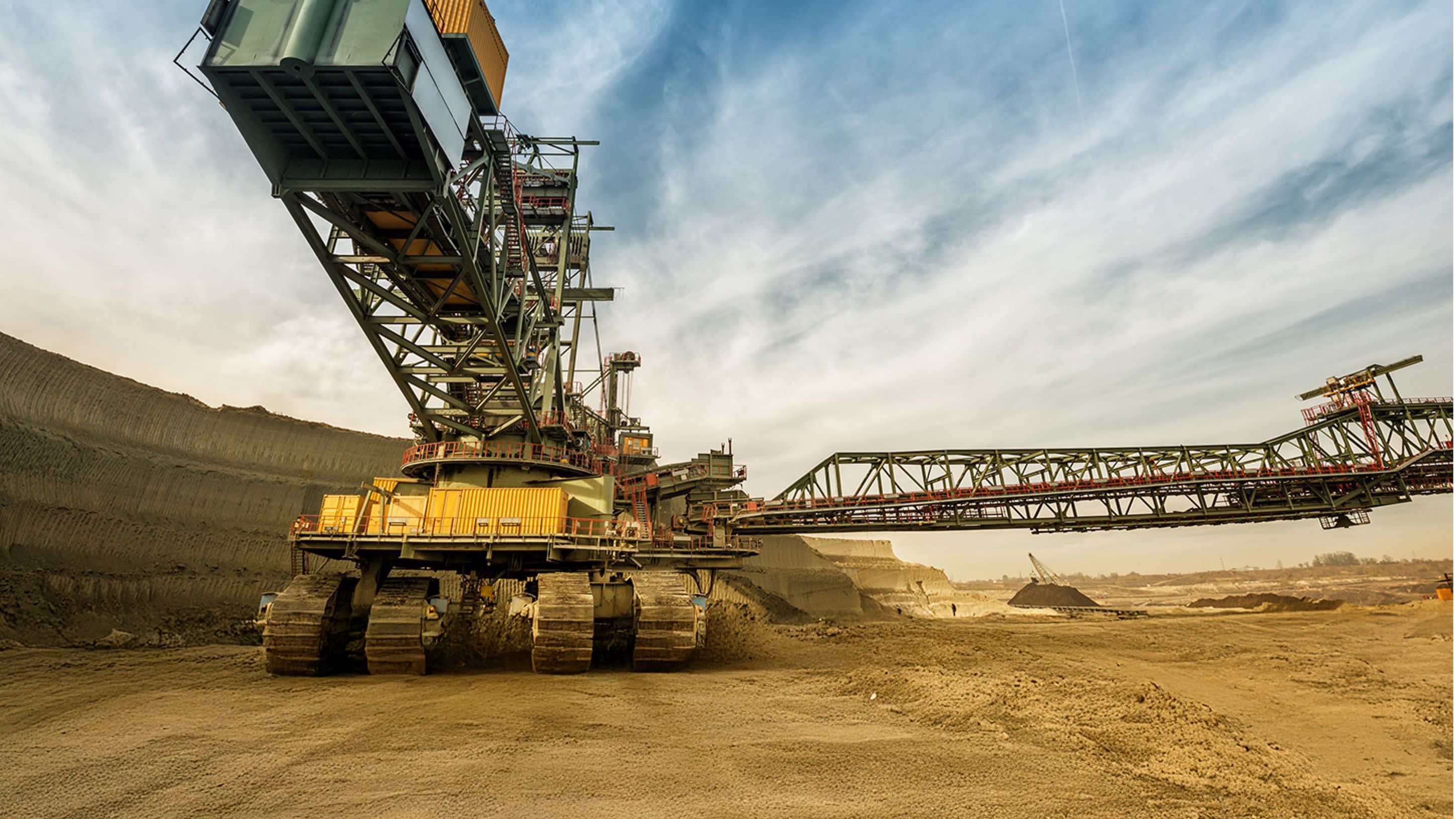 Large industrial mining machine in an open-pit mine under a blue sky with clouds