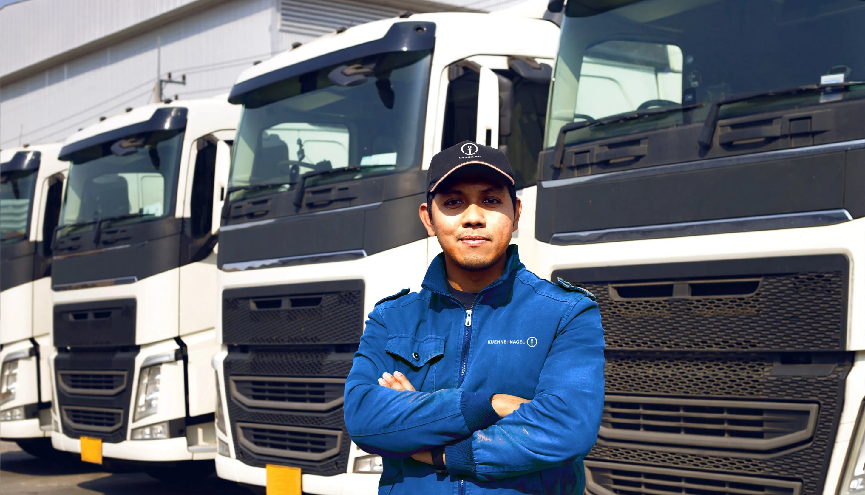 Driver in blue jacket in front of white trucks