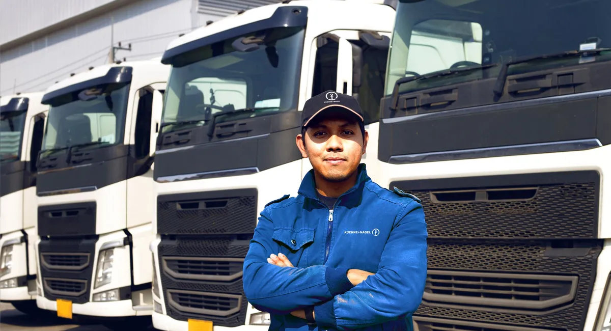 Driver in blue jacket in front of white trucks