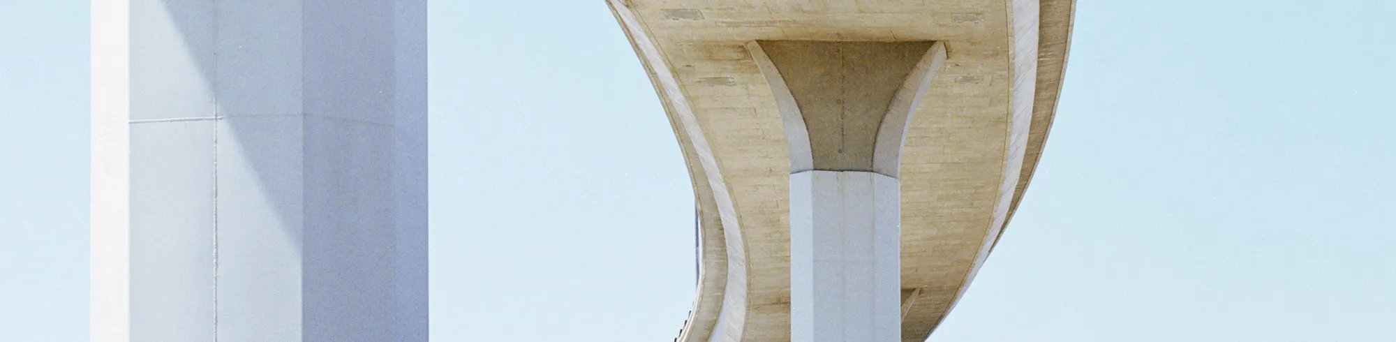 A blue Kuehne+Nagel truck is passing under the highway.