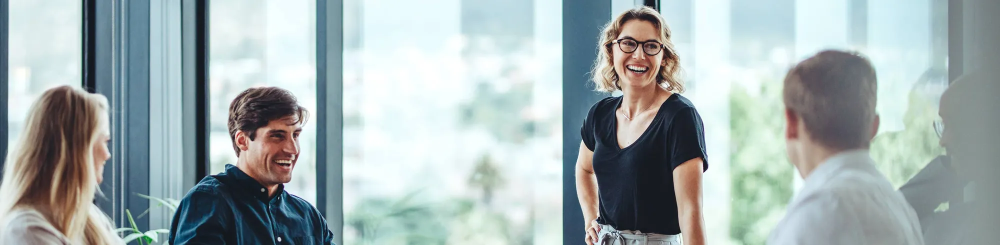 A group of professionals are laughing during a meeting in an office.
