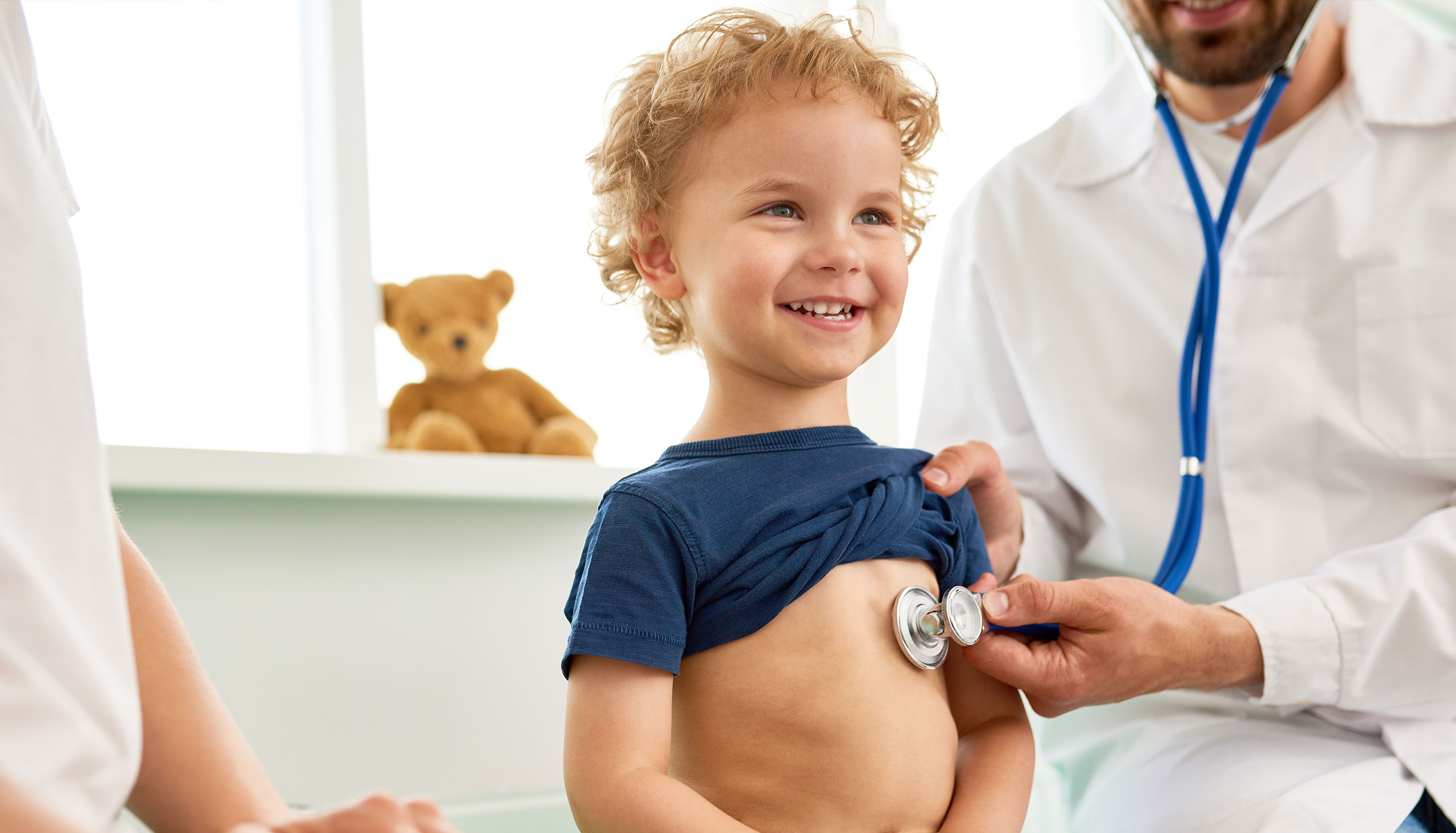 child in office being examined by doctor with a stethoscope.