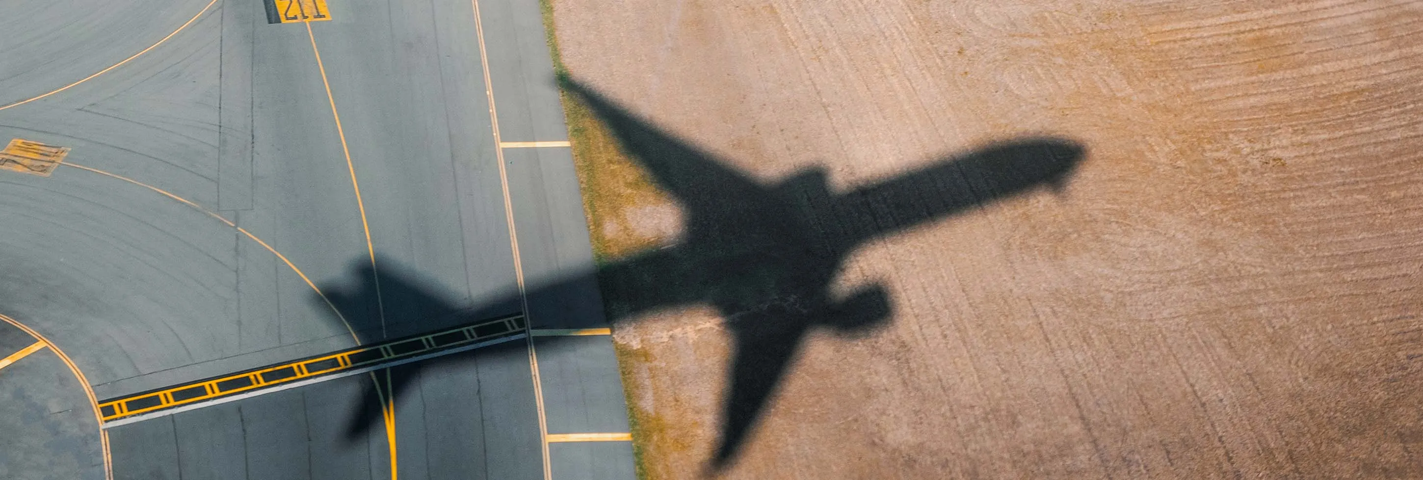 image with an track airport and the shadow of a plane