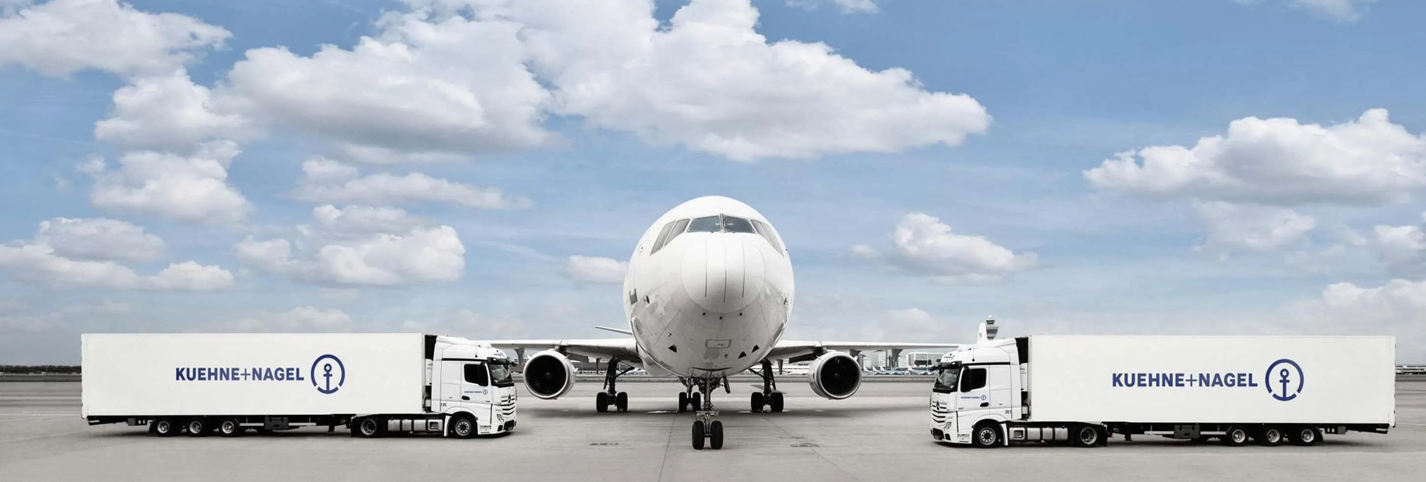 A large white plane positioned between two white trucks, ready for departure