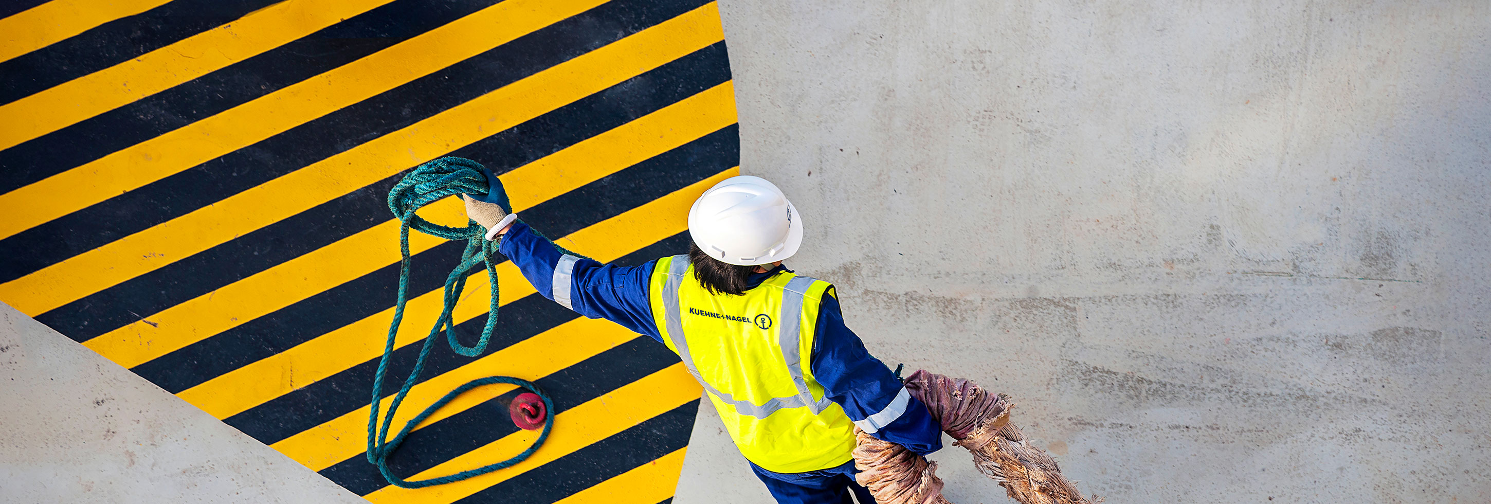 Trabalhador manual puxando corda de amarração em navio porta-contêineres, marinheiro asiático