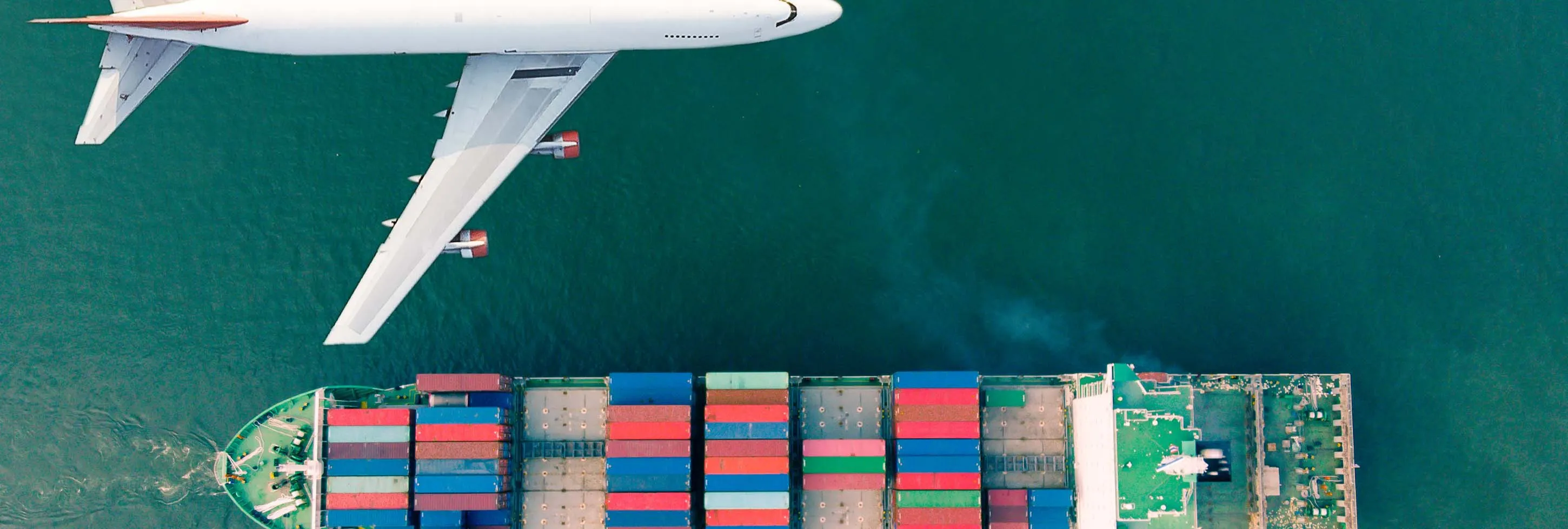 Big white plane flying above a big carrier ship
