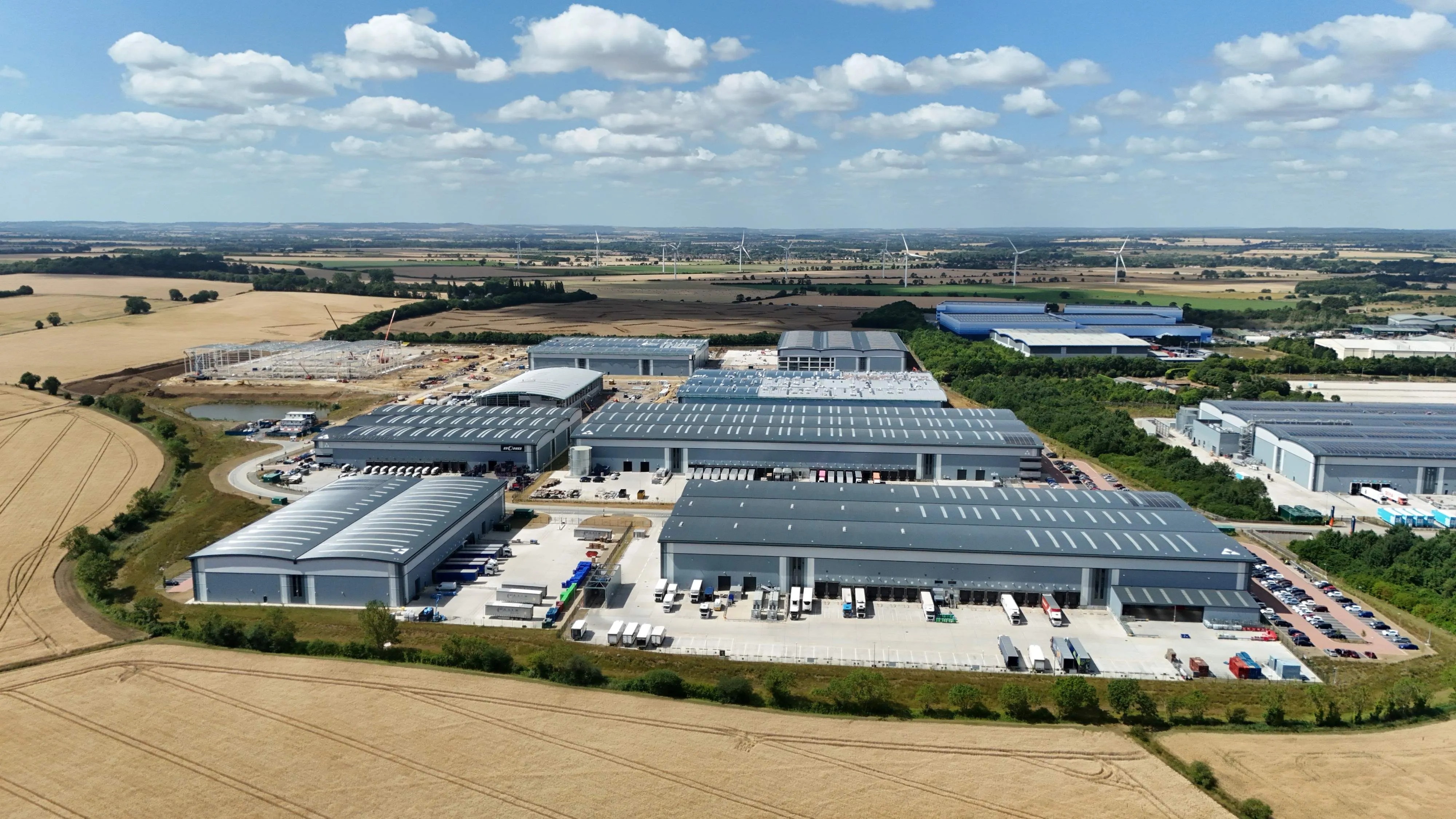 Aerial view of a large industrial facility with multiple warehouse and data centre buildings surrounded by transport infrastructure and agricultural land.