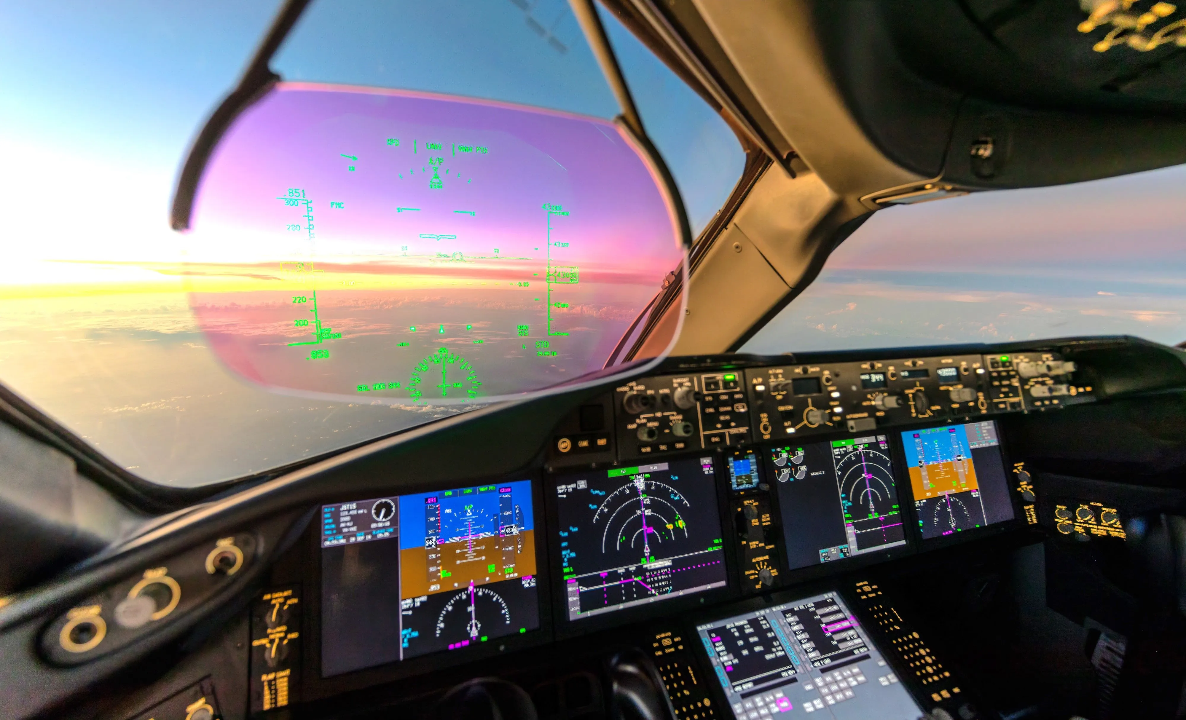 Aircraft cockpit with HUD and instrument panel during sunset.