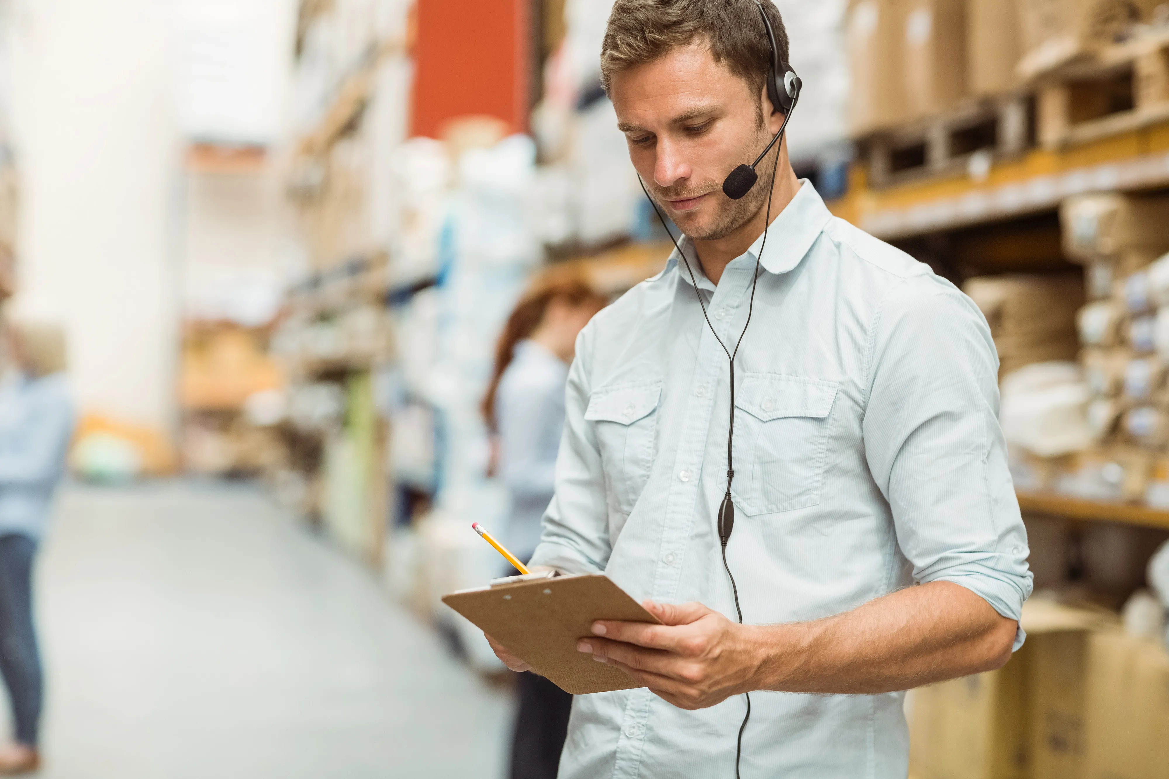 Worker in a warehouse with headset writing something on the board
