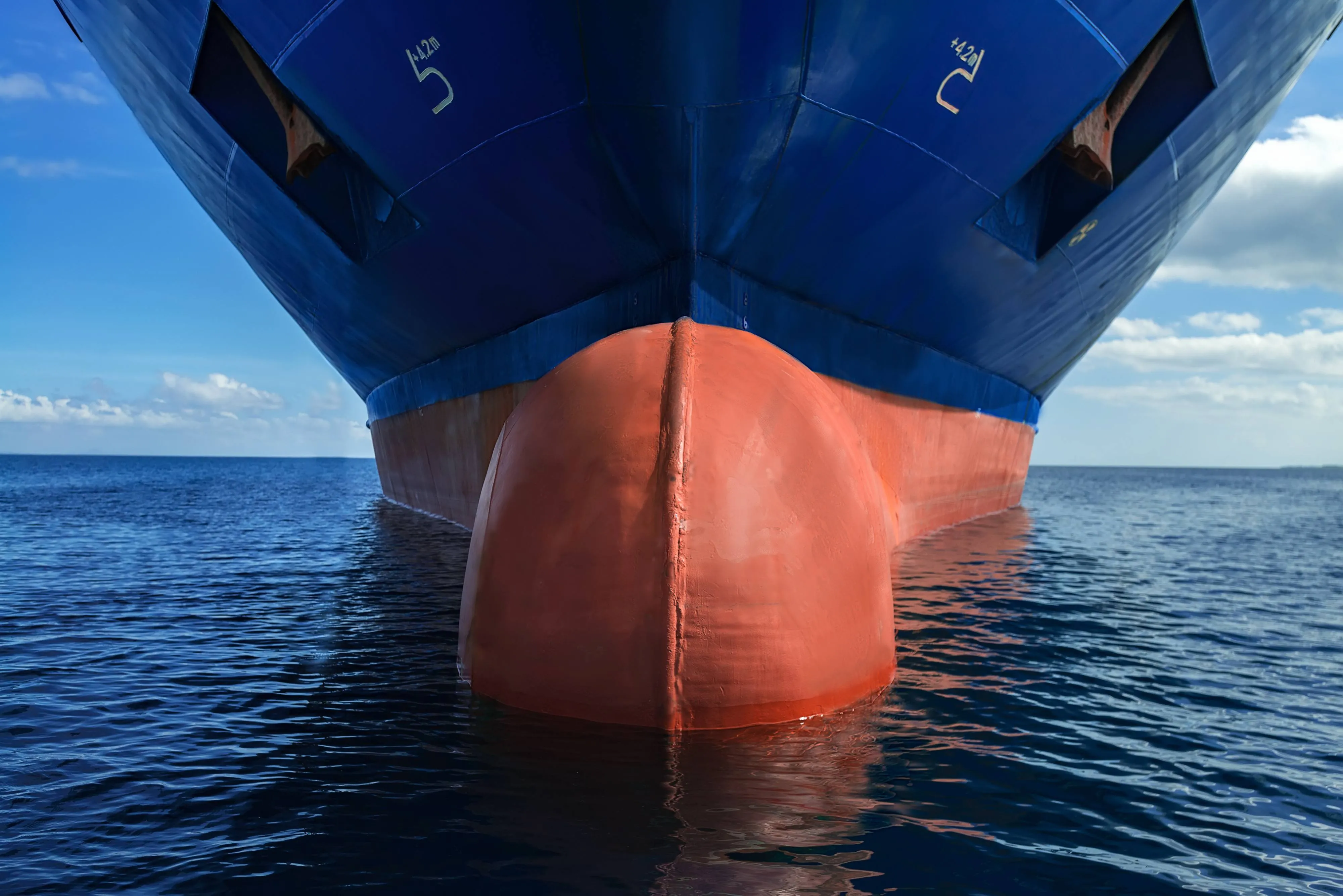 Close-up view of the front of a large blue and red ship floating on the ocean.