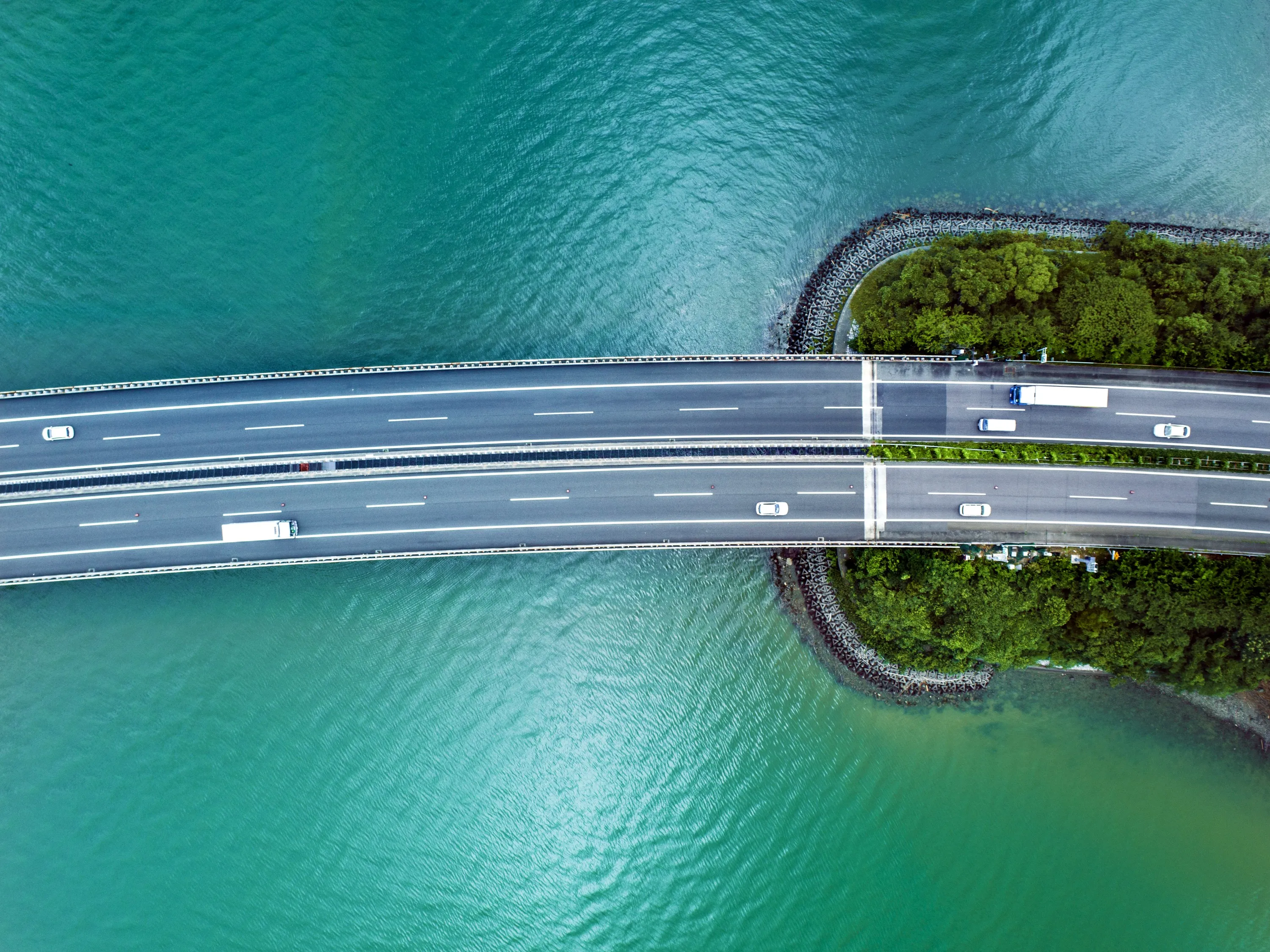Aerial view of a bridge with vehicles crossing over blue-green water