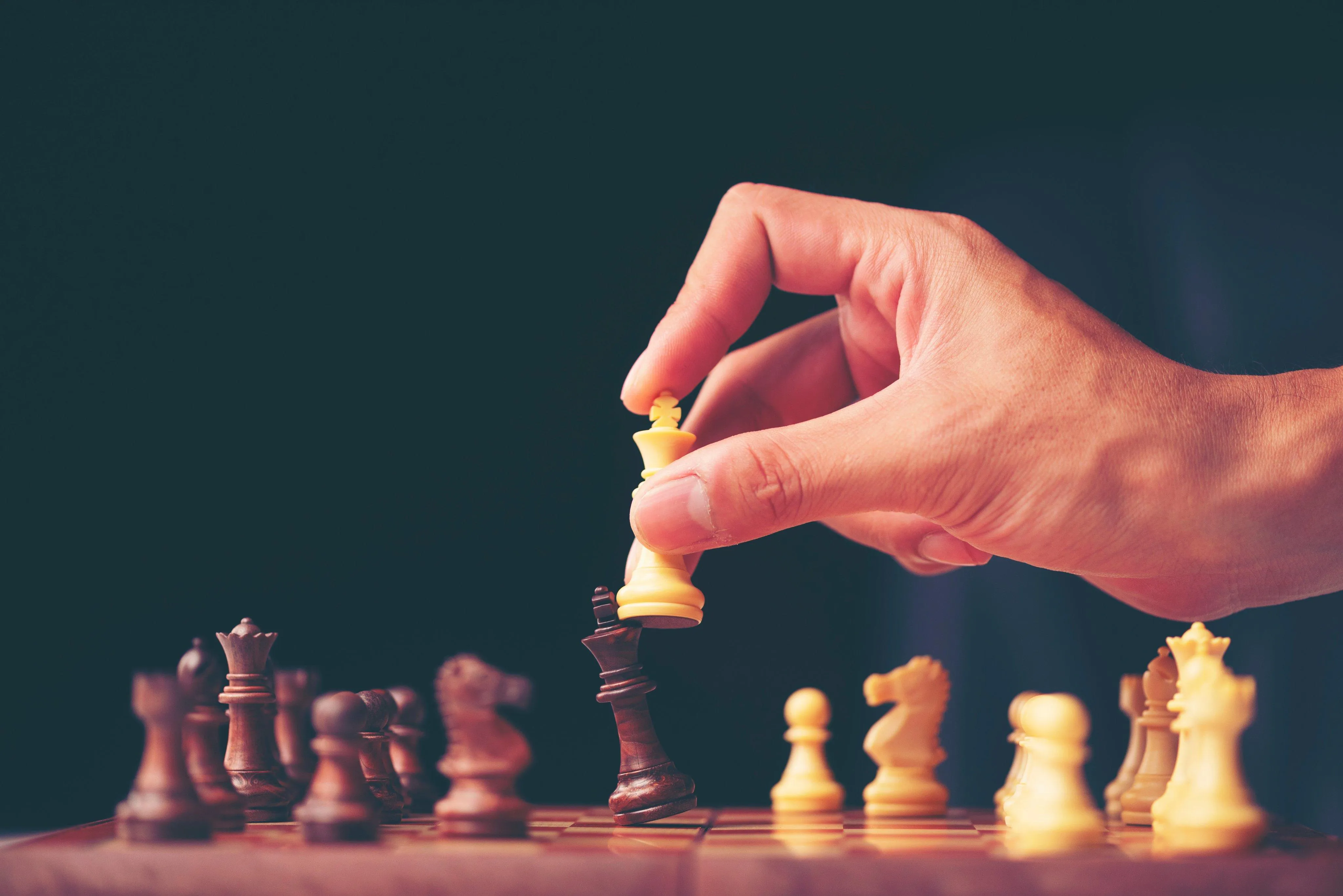 Hand of businessman moving chess figure in competition success play.