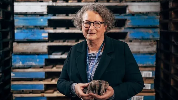 Petra holding an elephant figurine in front of wooden pallets